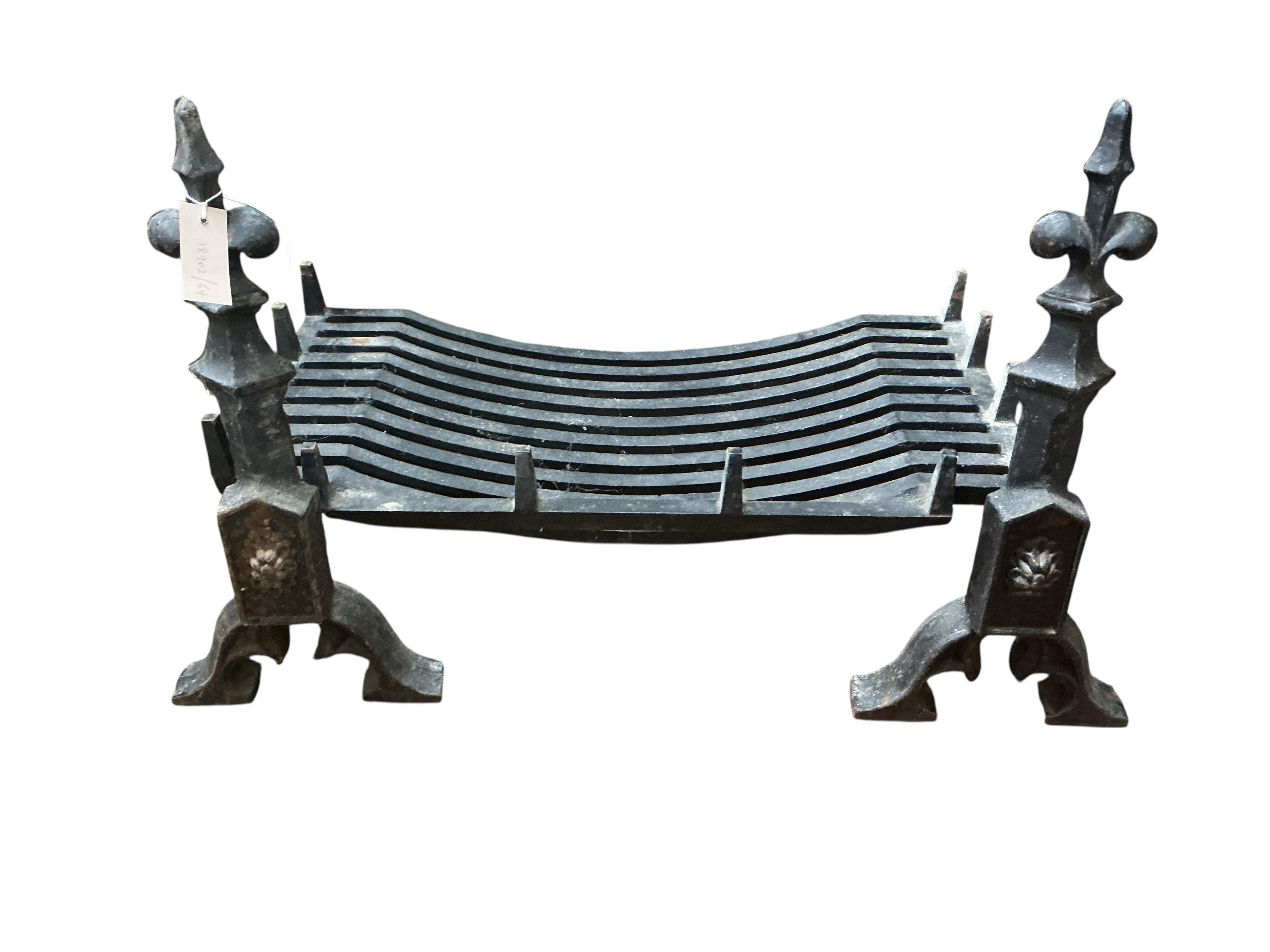 A wrought iron grate with fleur de lys dogs, width 76cm, depth 50cm, height 56cm (lacking one bolt)
